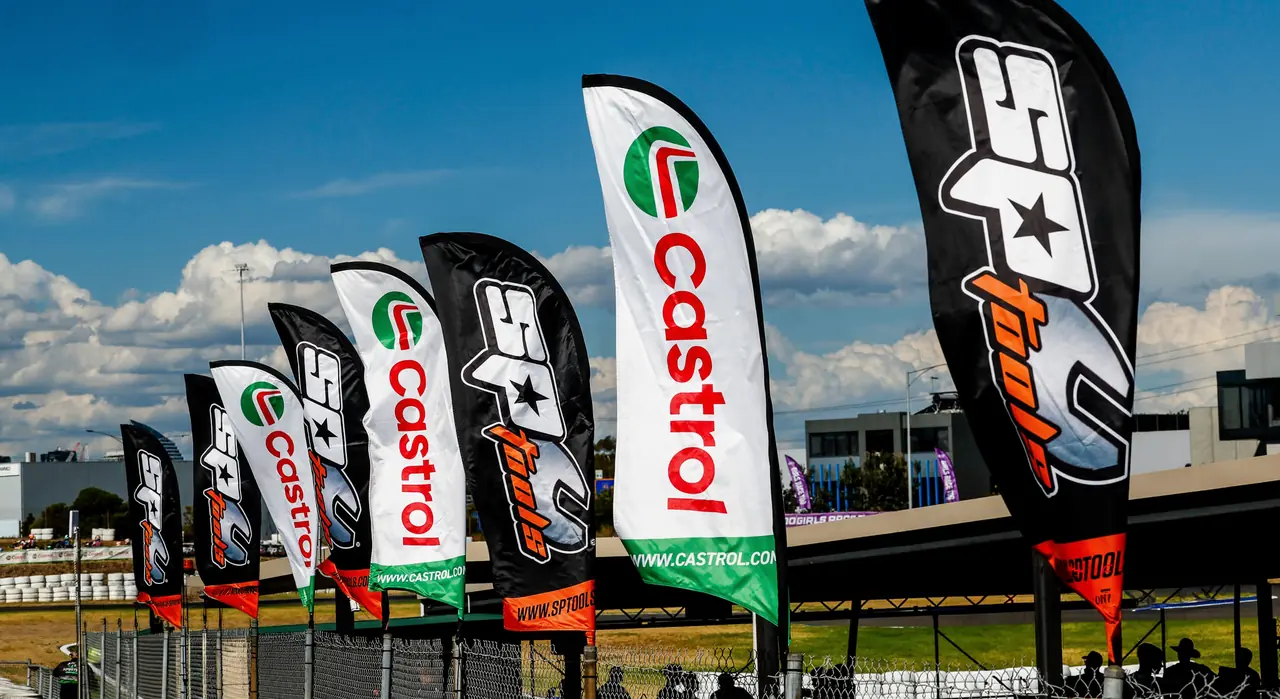 A row of branded feather and teardrop flags at a motorsport venue