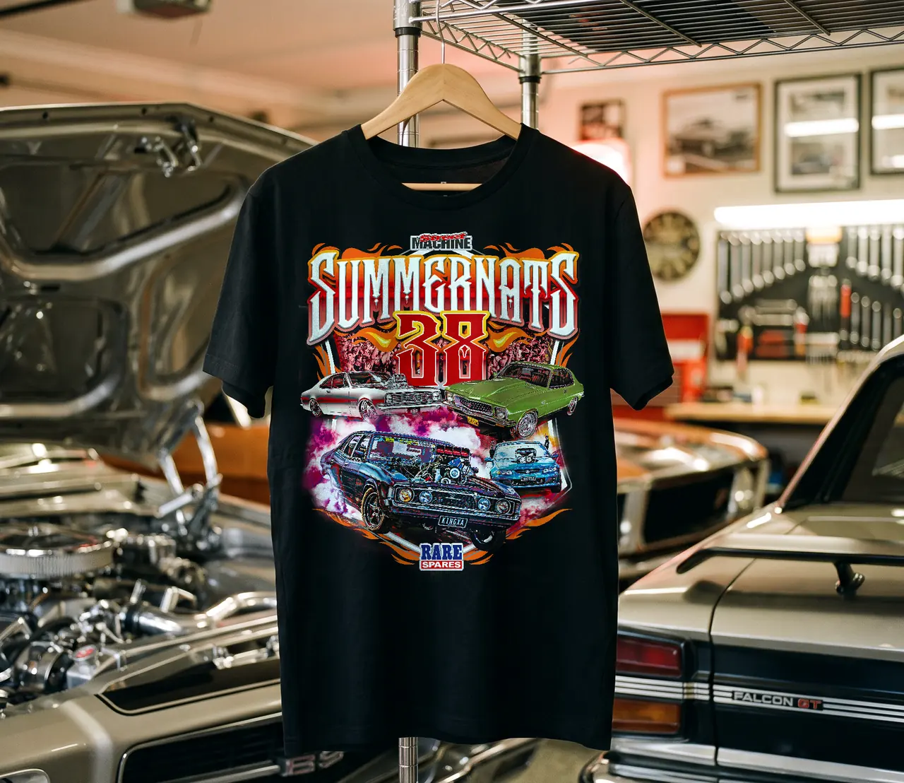 Black t-shirt with a full-colour illustrated design, hanging in a garage